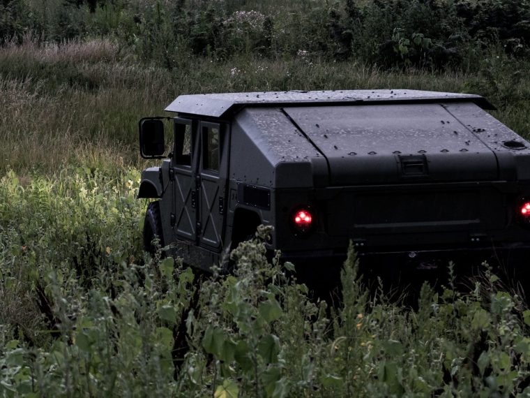 A blacked-out Humvee sitting in tall grass